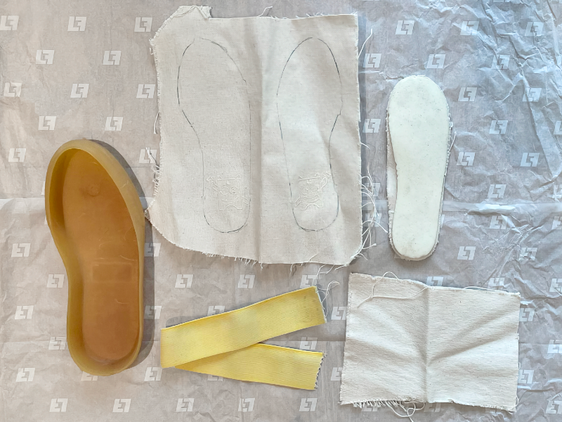 Close-up of natural, non-toxic shoe materials including organic cotton canvas and plant-dyed elastic laid flat on a sheet of paper