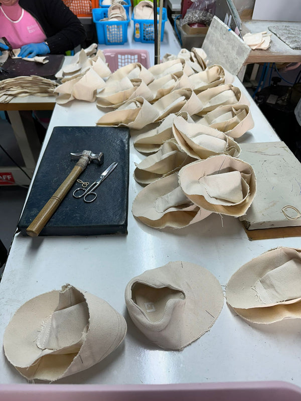 Worktable with shoe-making materials and tools in a workshop setting